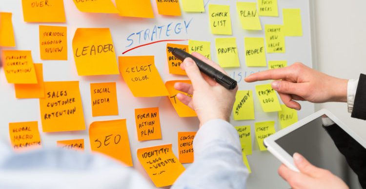 hands pointing to sticky notes on the wall