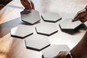 Hands arranging gray hexagon tiles on a table to represent Hiveology and how to build community in business