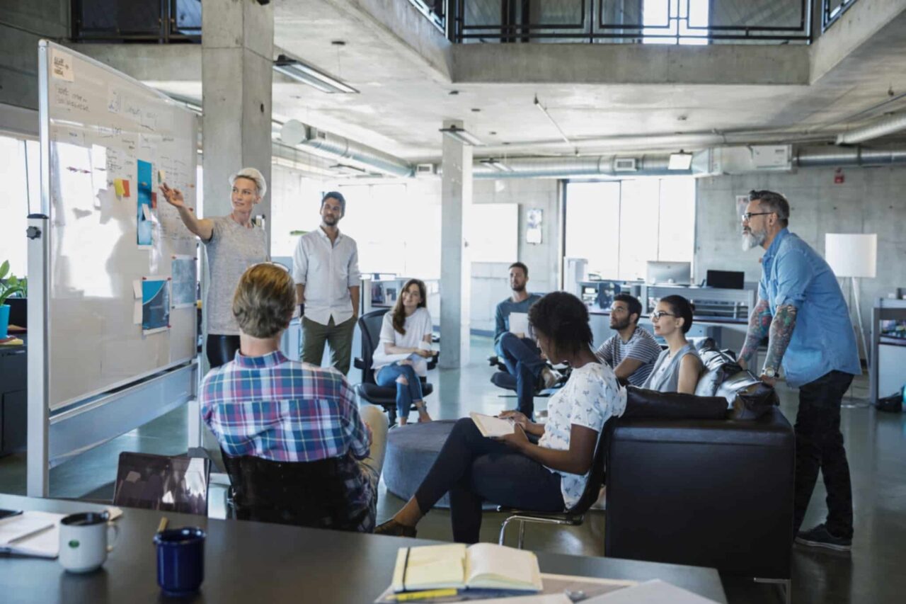Female leader facilitating a coaching session with diverse team in a modern office